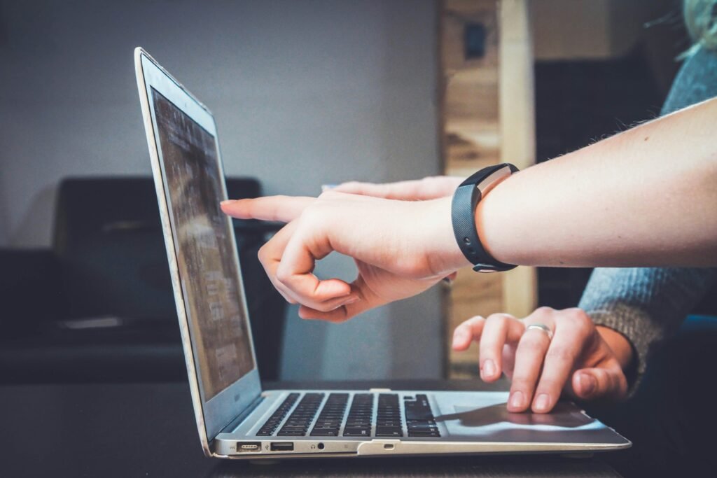 Two people collaborating on a laptop, one pointing at the screen